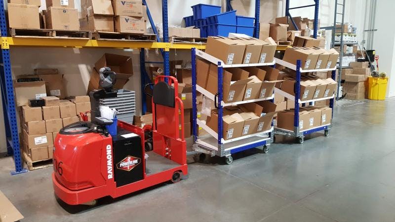 FlexQube Material Handling flow shelf carts connected to a tugger